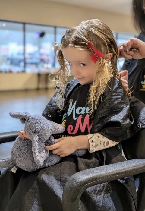 Girl holding a stuffed bunny during her haircut
