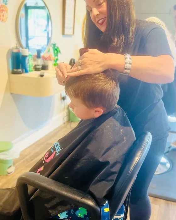 Stylist giving a young boy a haircut