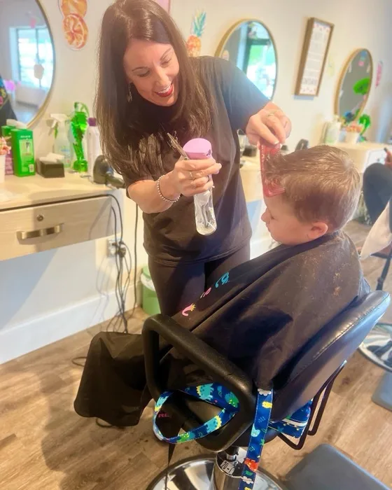 Stylist styling a boy's hair in front of a mirror